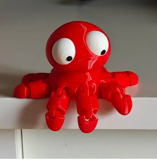 Mini Flexi Octopus escondido en un rincón del escritorio, figura de colección Gufis.